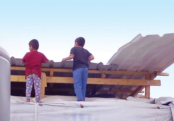 Two boys watch the demolition of their refugee camp as Lebanon fears building work inside tents could represent the start of resettlement or permanent residence of Syrian refugees. (Photo/Supplied)