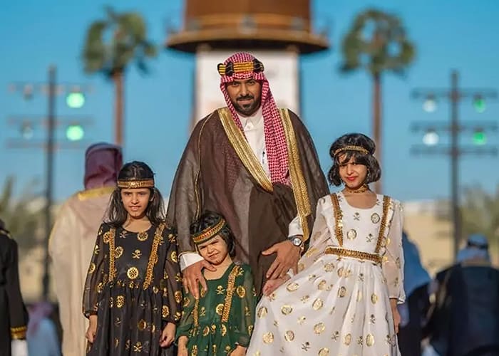 A Saudi man with his daughters wearing Saudi Arabia traditional clothing.