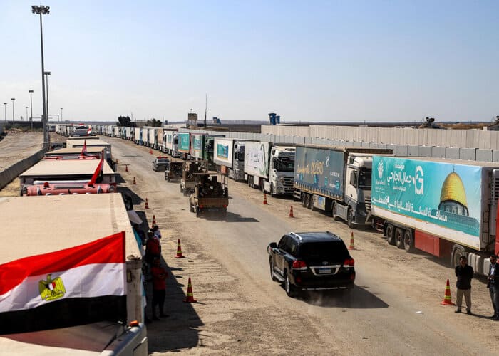 "Relief Trucks Halted at Open Crossing by Israeli Bombing