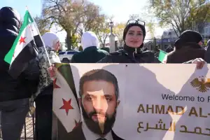 Syrian President Ahmed Al-Sharaa greets his supporters outside the White House.